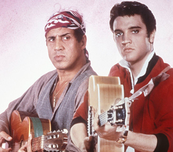 Adriano Celentano, lângă un poster al idolului său, Elvis Presley (1984)